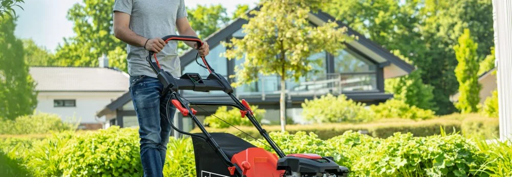 Person mit Rasenmäher im Garten